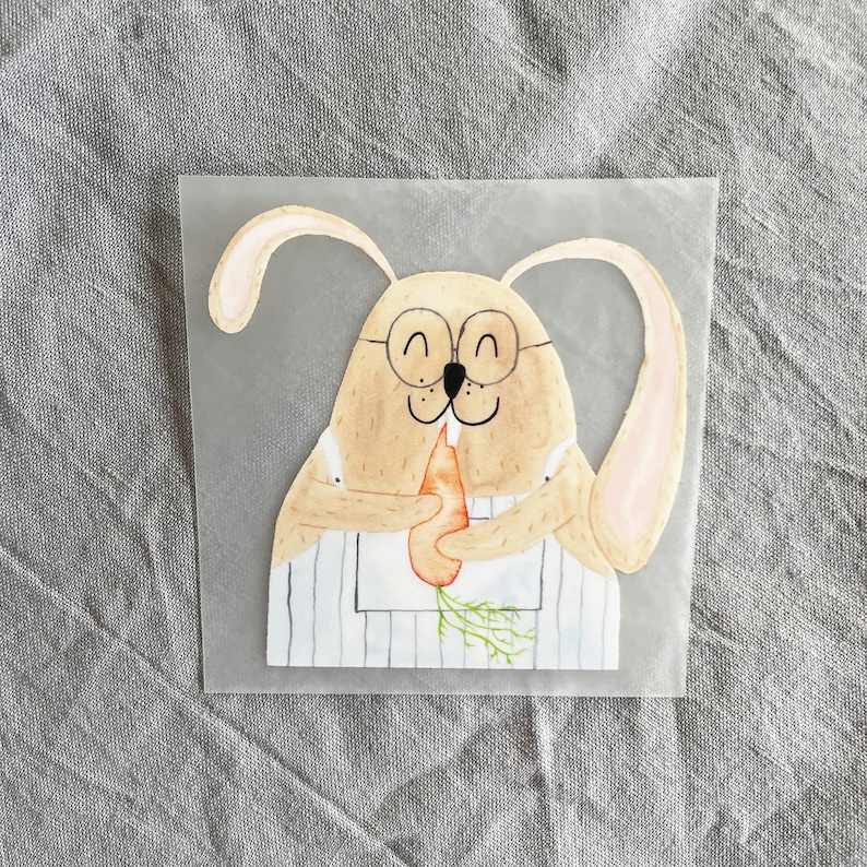 May include: A watercolor illustration of a brown bunny wearing glasses and a striped apron, holding a carrot in its paws.