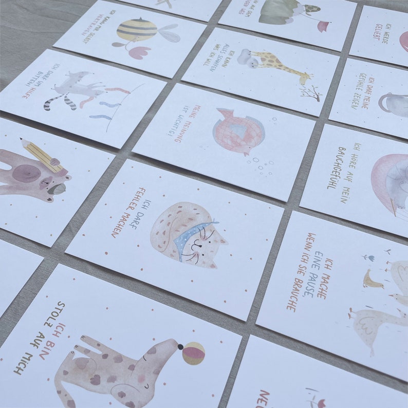 Op de afbeelding: Een set van 10 ge&iuml;llustreerde kaarten met aquareldieren en motiverende zinnen in het Duits. De kaarten tonen verschillende dieren, waaronder een kat, een hond, een vis, een bij, een giraffe en een gans. Elke kaart heeft een andere zin, zoals "Ich darf Fehler machen" (Ik mag fouten maken) en "Ich bin stolz auf mich" (Ik ben trots op mezelf).