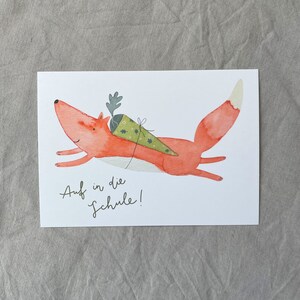 May include: A red fox with a green and white cone on its back runs towards the right. The text "Auf in die Schule!" is written below the fox.