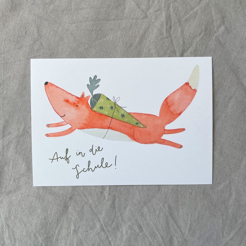 May include: A red fox with a green and white cone on its back runs towards the right. The text "Auf in die Schule!" is written below the fox.