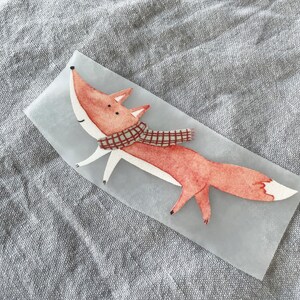 May include: A red fox with a plaid scarf is illustrated on a white background. The fox is walking with its tail curled up behind it.