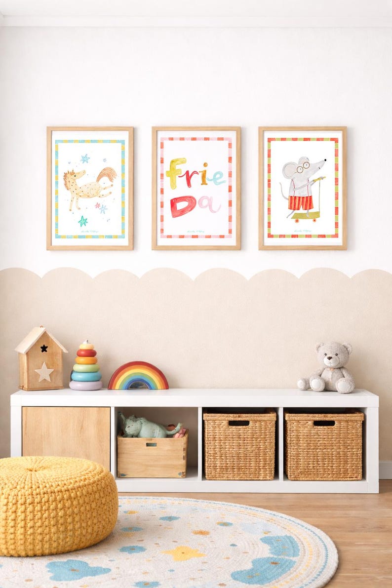 May include: Three framed watercolor prints with animal illustrations and the word "Friend" in colorful letters. Below, a white shelf holds toys, including a wooden house, a rainbow, and a teddy bear. A yellow pouf and a patterned rug complete the scene.