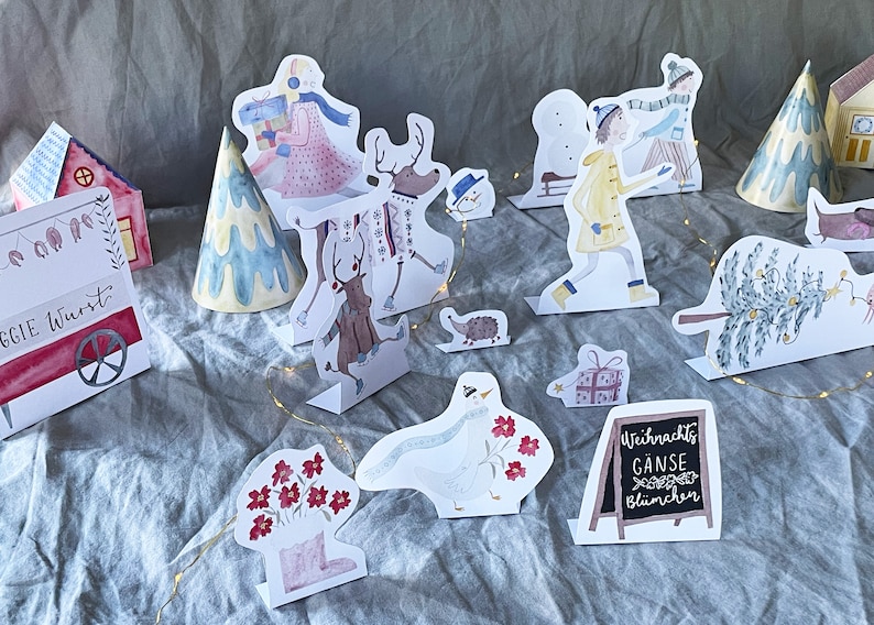 May include: A set of Christmas-themed paper cutouts, including a reindeer, a snowman, a goose, a tree, a house, and a sign that reads "Weihnachts G&auml;nse Bl&uuml;mchen".