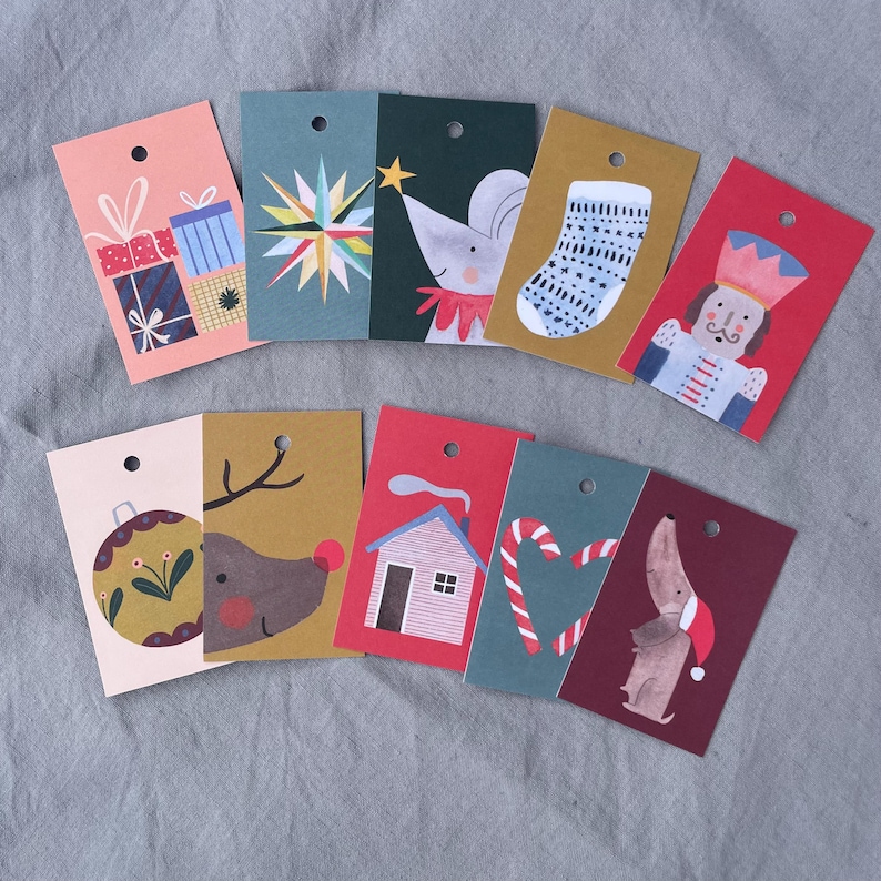 K&ouml;nnte beinhalten: Eine Sammlung farbenfroher Weihnachtsetiketten mit verschiedenen festlichen Illustrationen. Designs umfassen Geschenkpakete, einen Stern, eine Maus mit Stern, einen Strumpf, einen Nussknacker, eine Kugel, ein Rentier, ein Haus, Zuckerstangen und einen Dackel.