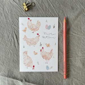Pu&ograve; includere: Un biglietto bianco con un'illustrazione ad acquerello di galline e pulcini. Il biglietto ha il testo "Frohe Ostern" scritto in inchiostro nero.