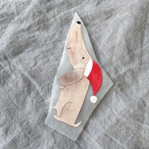 May include: A brown and white dog wearing a red Santa hat. The dog is standing on its hind legs and has its front paws raised.