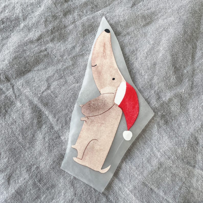 May include: A brown and white dog wearing a red Santa hat. The dog is standing on its hind legs and has its front paws raised.