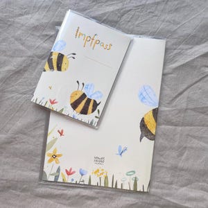 May include: A cream-colored vaccination record holder and a matching document cover, both featuring watercolor illustrations of yellow and black bumblebees, blue wings, and colorful wildflowers. The smaller cover has the text Impfpass printed.