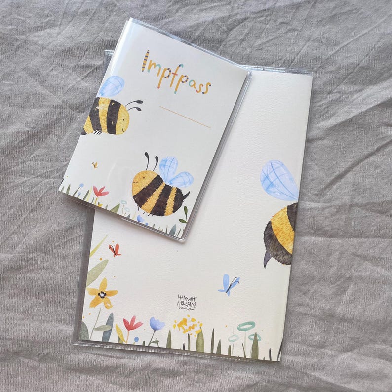 May include: A cream-colored vaccination record holder and a matching document cover, both featuring watercolor illustrations of yellow and black bumblebees, blue wings, and colorful wildflowers. The smaller cover has the text Impfpass printed.