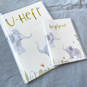 May include: Two colourful folders with elephant illustrations and the text "U-Heft" and "Impfpass".