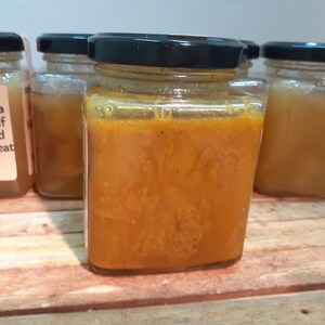 May include: Four glass jars filled with honey. The jar in the center is filled with a darker, more viscous honey. The label on the jar on the left reads "Honey Crystallization is a natural process. If you want a liquid honey, do not heat over 40 C / 104 F."