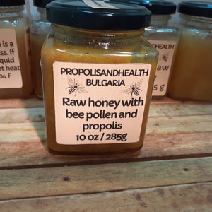 May include: A glass jar of raw honey with bee pollen and propolis from Bulgaria. The label reads "Propolis and Health Bulgaria" with a bee illustration. The jar contains 10 ounces or 285 grams of honey.