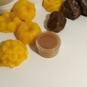 Puede incluir: Una variedad de ceras para fundir de color amarillo y marrón en diferentes formas, incluyendo una rosa, una calabaza y un diseño de espiral. También hay un pequeño recipiente de cera marrón.