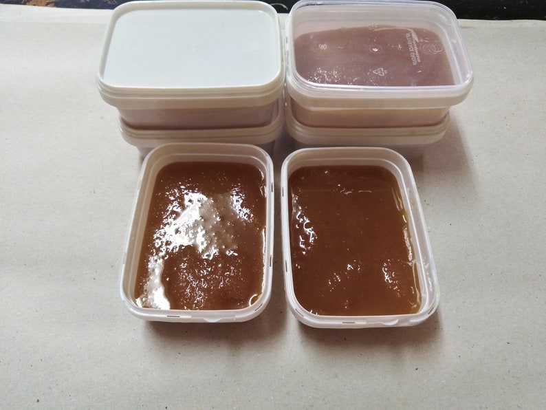 May include: Four white plastic containers with lids, two filled with a brown liquid, and two empty.