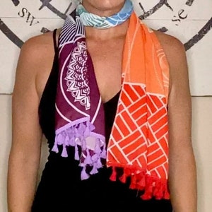 May include: A colorful scarf with a geometric pattern and tassels. The scarf is made of a soft, lightweight fabric and is perfect for adding a pop of color to any outfit.