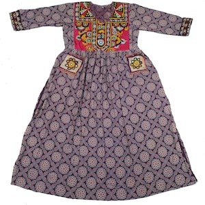 Puede incluir: Un vestido largo de color morado con estampado floral y bordados coloridos alrededor del cuello y los bolsillos.