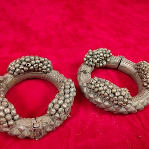 Può includere: Due braccialetti d'argento con disegni intricati. Ogni braccialetto è adornato da un gruppo di piccole perle rotonde e da una superficie testurizzata.