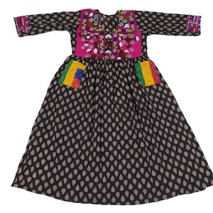 May include: A black dress with a pink embroidered bodice and colorful trim. The dress has a gathered skirt with a teardrop pattern and two colorful pockets.