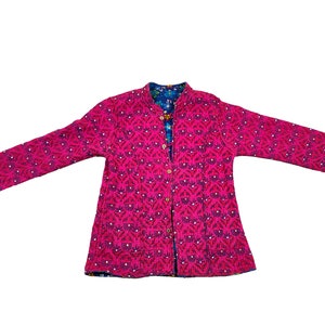 May include: A magenta quilted jacket with a floral pattern. The jacket has long sleeves and a mandarin collar. The interior lining is a blue floral print. The jacket is buttoned down the front with wooden buttons.