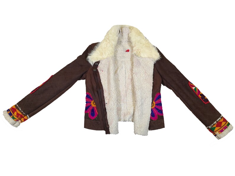 K&ouml;nnte beinhalten: Braune Jacke mit cremefarbenem Shearling-Futter und -Kragen. Die Jacke hat bunte Blumen- und geometrische Stickereidetails an den &Auml;rmeln und der Vorderseite. Die Jacke hat einen Knopfverschluss und ein Steppmuster.