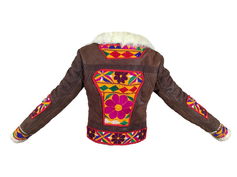 K&ouml;nnte beinhalten: Braune Jacke mit farbenfrohen Blumenstickereien auf dem R&uuml;cken und den &Auml;rmeln. Die Jacke hat einen wei&szlig;en Fellkragen und -b&uuml;ndchen. Die Stickerei weist rote, gelbe, rosa und blaue Akzente auf. Die Jacke besteht aus einem strukturierten Material.