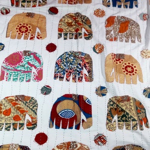 K&ouml;nnte beinhalten: Wei&szlig;er Baumwollstoff mit einem sich wiederholenden Muster aus bunten Patchwork-Elefanten-Designs. Jeder Elefant besteht aus verschiedenen Stoffen mit verschiedenen Mustern und Farben.