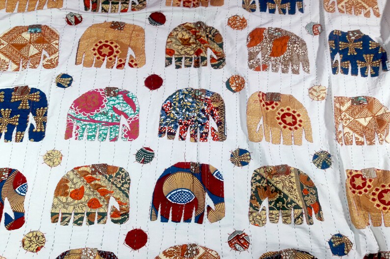 K&ouml;nnte beinhalten: Wei&szlig;er Baumwollstoff mit einem sich wiederholenden Muster aus bunten Patchwork-Elefanten-Designs. Jeder Elefant besteht aus verschiedenen Stoffen mit verschiedenen Mustern und Farben.