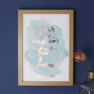 May include: A framed print with a watercolor background in shades of blue and green. The words "your custom text here" are written in gold foil lettering. The print is ready to be personalized with your own text.