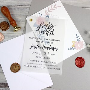 Op de afbeelding: Een transparante babyborrel uitnodiging met een bloemenpatroon en de tekst "hello world" en "Jenifer Henderson" in zwart gedrukt. De uitnodiging bevat ook de datum "June 13 | 2020" en de tijd "AT 3 O'CLOCK".