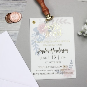Op de afbeelding: Een babyshower-uitnodiging met een bloemenontwerp en gouden letters. De uitnodiging luidt "hello world" en bevat de naam "Jenifer Henderson" en de datum "June 13, 2020".