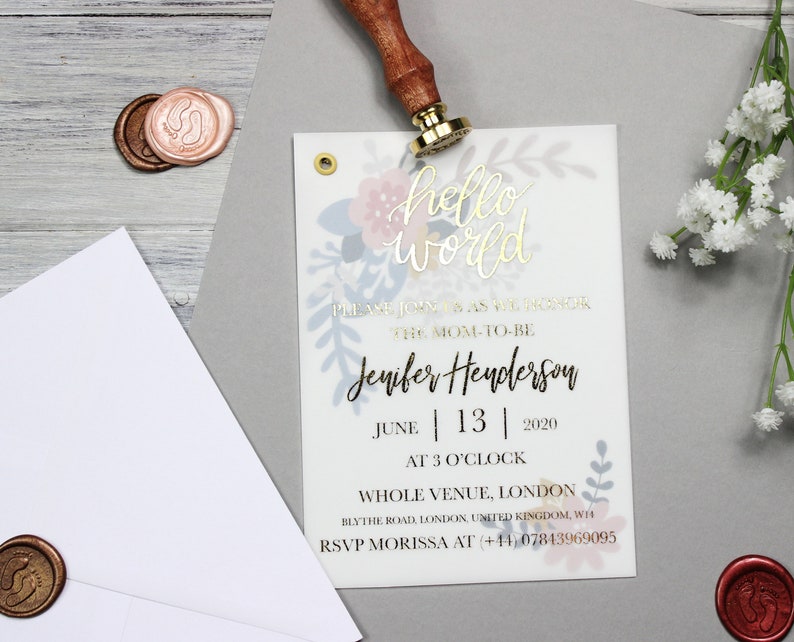 Op de afbeelding: Een babyshower-uitnodiging met een bloemenontwerp en gouden letters. De uitnodiging luidt "hello world" en bevat de naam "Jenifer Henderson" en de datum "June 13, 2020".