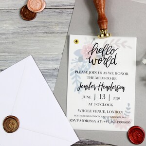 Op de afbeelding: Een babyshower-uitnodiging met een bloemenontwerp en de tekst "hello world". De uitnodiging is voor Jenifer Henderson en staat gepland voor 13 juni 2020 om 15:00 uur. De locatie is Whole Venue, Londen, Blythe Road, Londen, Verenigd Koninkrijk, WH. Het RSVP-nummer is +41 07843969095.