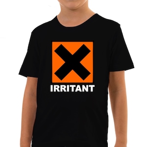 Op de afbeelding: Zwart T-shirt met een oranje vierkant met een zwarte X en het woord "IRRITANT" in witte letters.