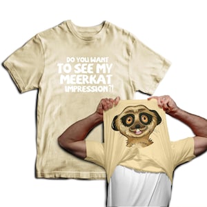 May include: A beige t-shirt with the text "Do you want to see my meerkat impression?" printed in white. A person is wearing the shirt and pulling it up to reveal a cartoon meerkat face printed on a beige t-shirt underneath.