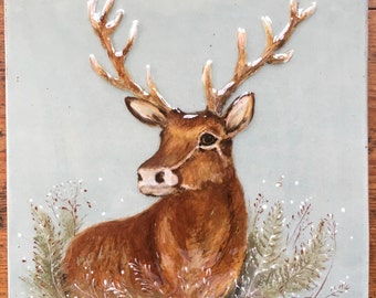 May include: A ceramic tile with a painted image of a brown deer with large antlers. The deer is surrounded by white and brown foliage on a light blue background.