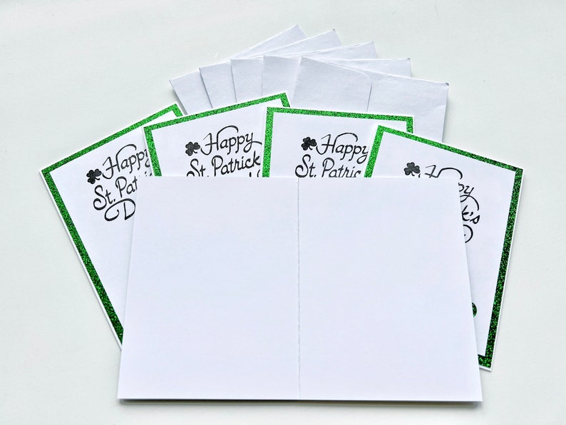 May include: A stack of blank greeting cards with a green glitter border and the text "Happy St. Patrick's Day" printed on the front.