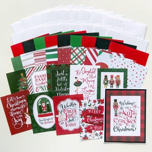 May include: A collection of Christmas cards with various designs and text, including "Merry Christmas to You" and "Wishing You a Nutcracker Christmas." The cards feature red, green, and white color schemes, with matching envelopes.