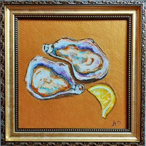 May include: An oil painting of two open oysters and a lemon wedge on a metallic gold background, enclosed in an ornate gold frame. The oysters feature textured brushstrokes in shades of white, blue, and brown, while the lemon is bright yellow.