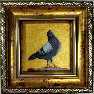 Puede incluir: Una pequeña pintura de una paloma gris con plumas de cuello iridiscentes en tonos violeta y azul, de pie sobre una repisa frente a un fondo dorado brillante, dentro de un marco dorado envejecido y ornamentado con un borde en relieve.