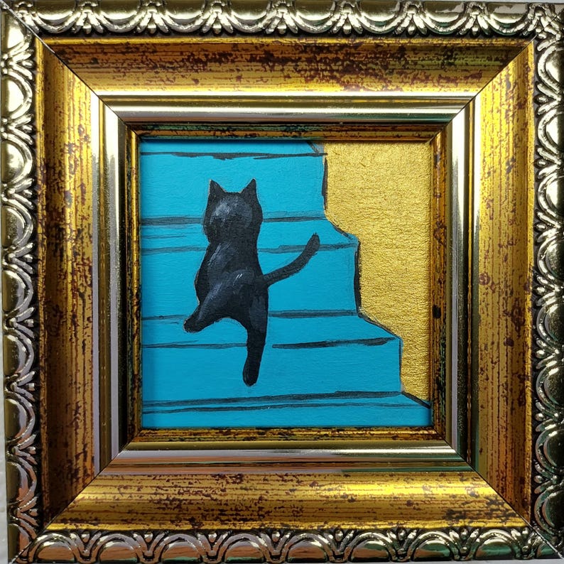May include: A black cat painted on a blue background with gold accents, walking up a set of stairs. The cat is in a gold frame.