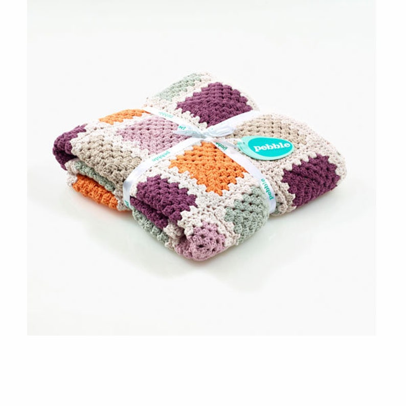 Peut inclure: Une couverture pour b&eacute;b&eacute; en crochet multicolore avec un ruban blanc et une &eacute;tiquette indiquant "Pebble".