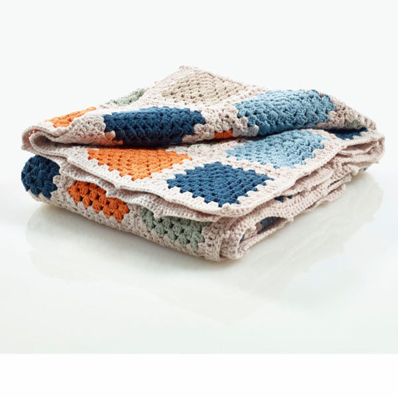 Peut inclure: Une couverture en crochet avec un motif patchwork compos&eacute; de carr&eacute;s dans des tons de bleu, vert, orange et beige.
