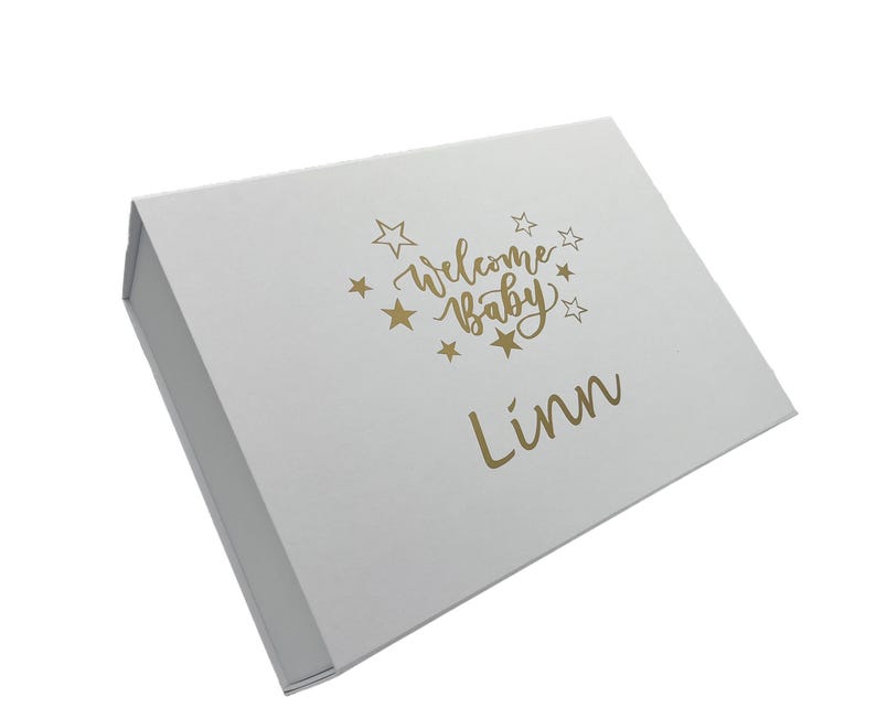 Peut inclure: Bo&icirc;te cadeau blanche avec inscription dor&eacute;e "Welcome Baby Linn" entour&eacute;e d'&eacute;toiles.