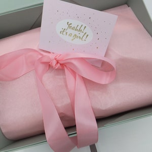 Peut inclure: Une bo&icirc;te cadeau vert clair avec un ruban rose et du papier de soie. La bo&icirc;te a une carte sur le dessus qui dit "Yeahhh! C'est une fille !"