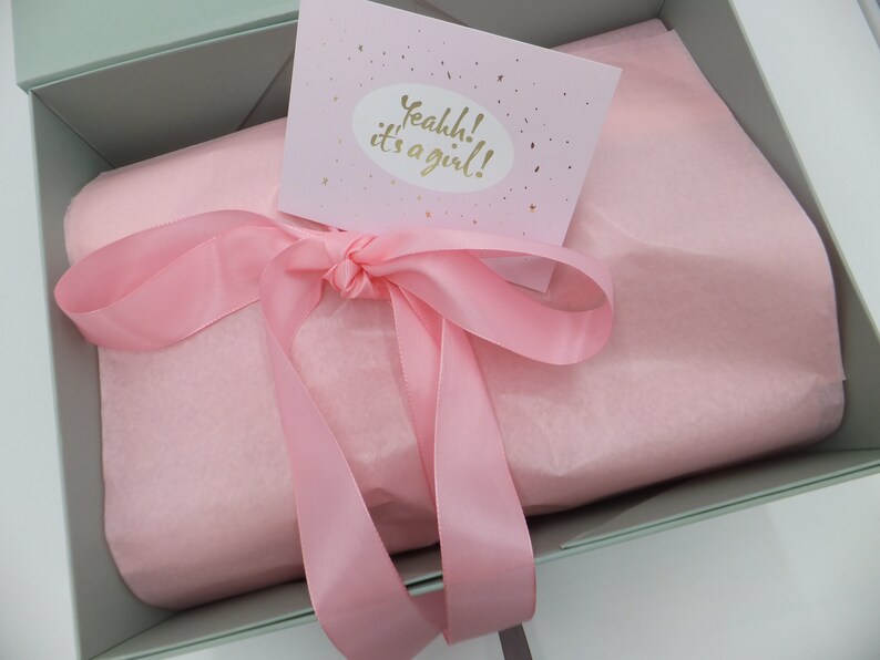 Peut inclure: Une bo&icirc;te cadeau vert clair avec un ruban rose et du papier de soie. La bo&icirc;te a une carte sur le dessus qui dit "Yeahhh! C'est une fille !"