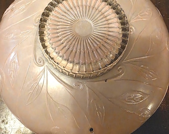 May include: A vintage, off-white glass ceiling light fixture with a leaf pattern. The fixture has a clear glass center and a decorative rim. The light fixture is likely from the mid-century era.