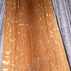 May include: A rectangular piece of wood with a warm brown hue, featuring a prominent wood grain pattern and lighter-colored streaks. The wood has knots and natural imperfections, with the date "11.24.2025" visible in the lower right corner. This piece is likely for woodworking or home decor.