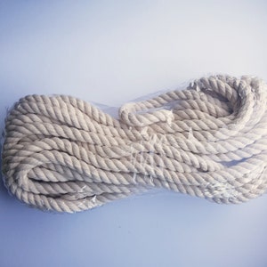 May include: A close-up of a white cotton rope packaged in clear plastic. The rope is coiled and ready to be used for crafting, macrame, or other projects.