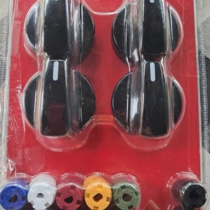 May include: A package of replacement stove knobs and burner caps. The knobs are black with a white indicator line. The burner caps are blue, white, red, yellow, green, and black. The packaging is red and clear plastic.