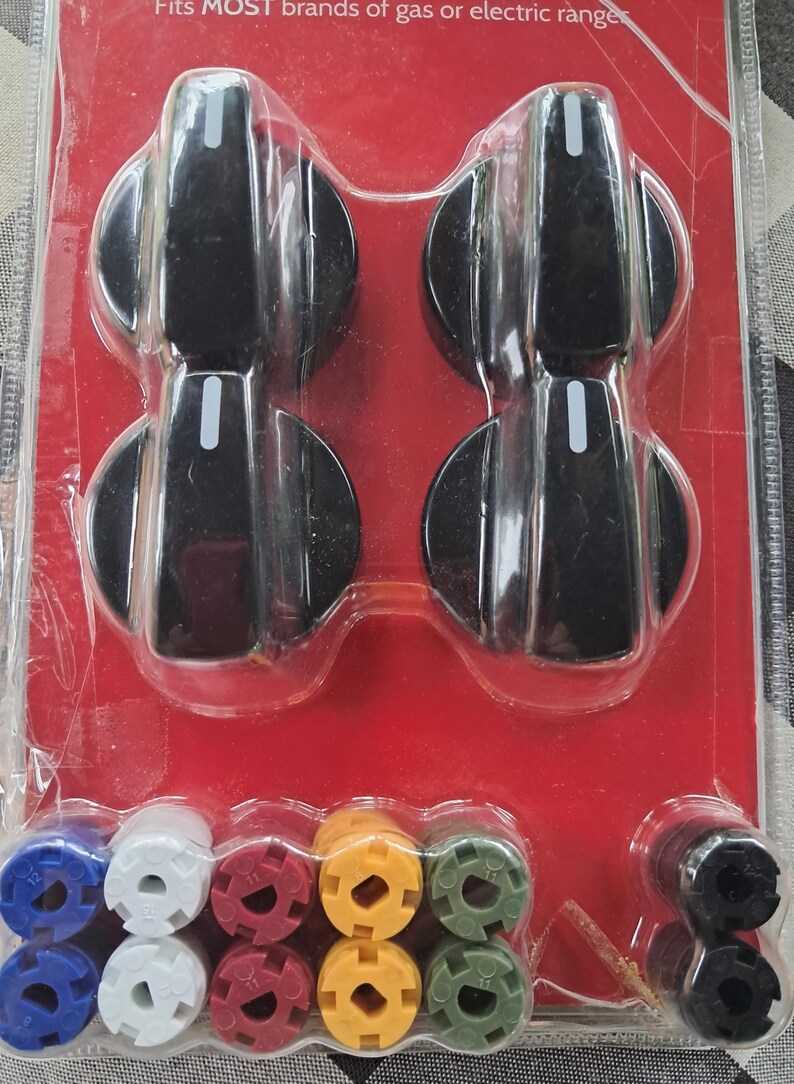 May include: A package of replacement stove knobs and burner caps. The knobs are black with a white indicator line. The burner caps are blue, white, red, yellow, green, and black. The packaging is red and clear plastic.